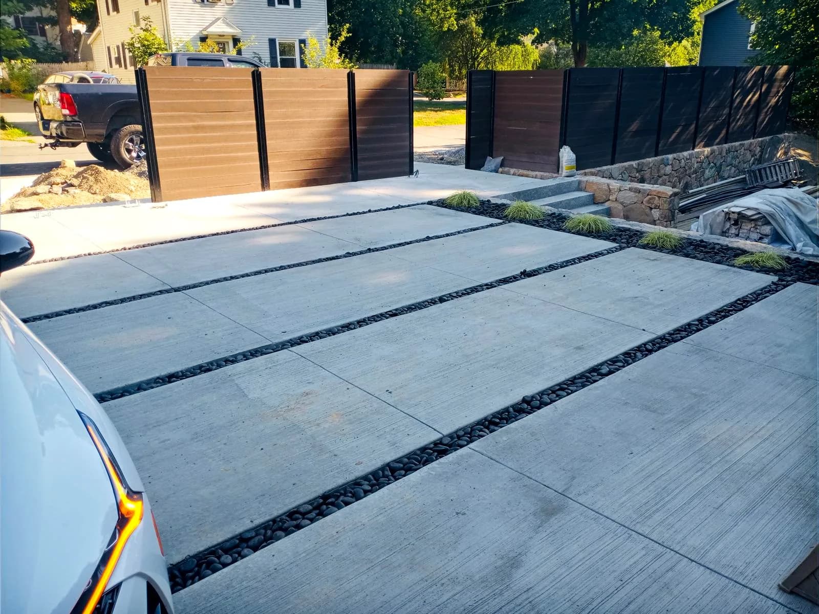 Modern concrete driveway featuring a river-rock accent strip along the edge