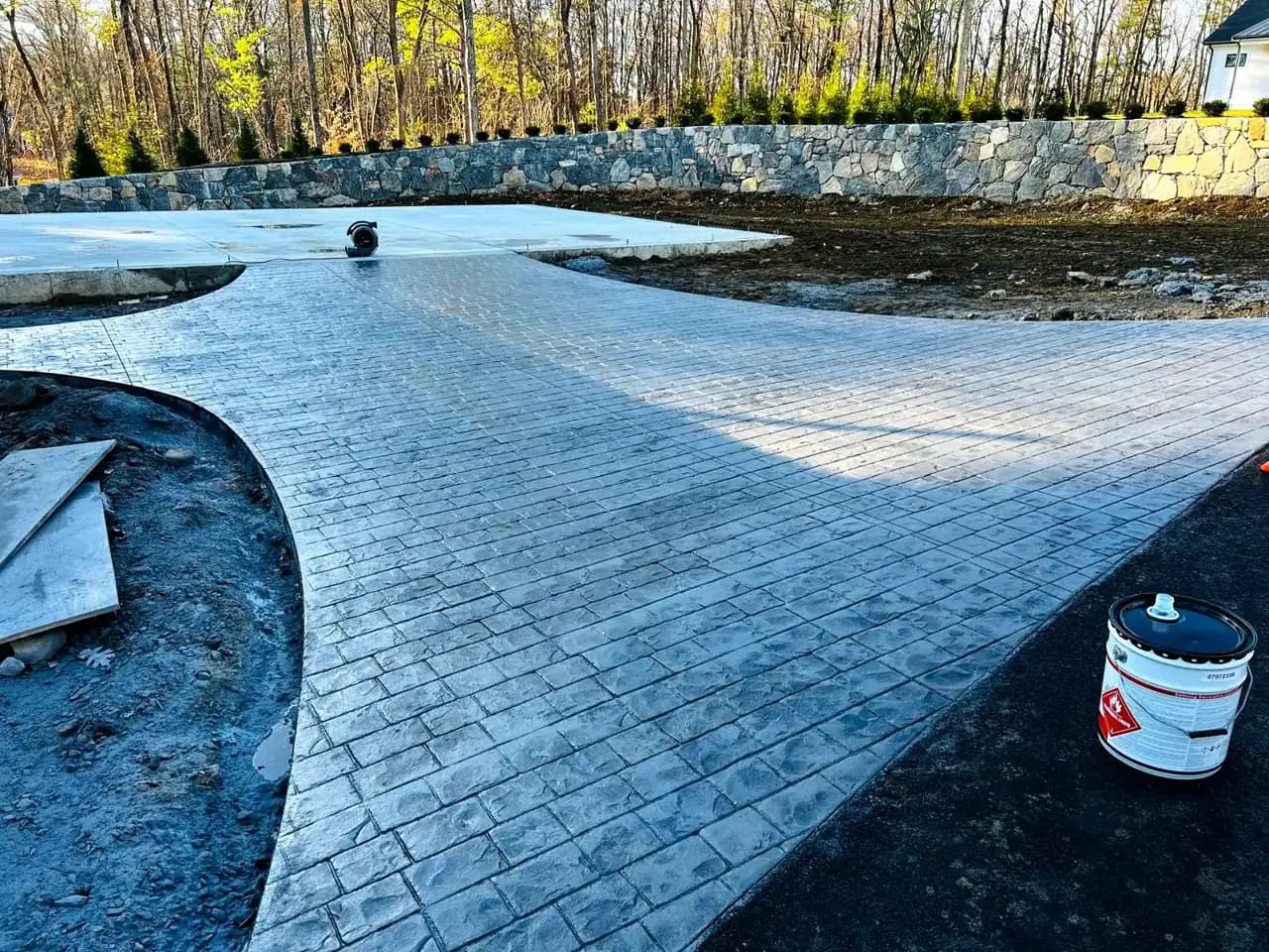 Stamped concrete driveway and patio installation in progress, pattern work underway